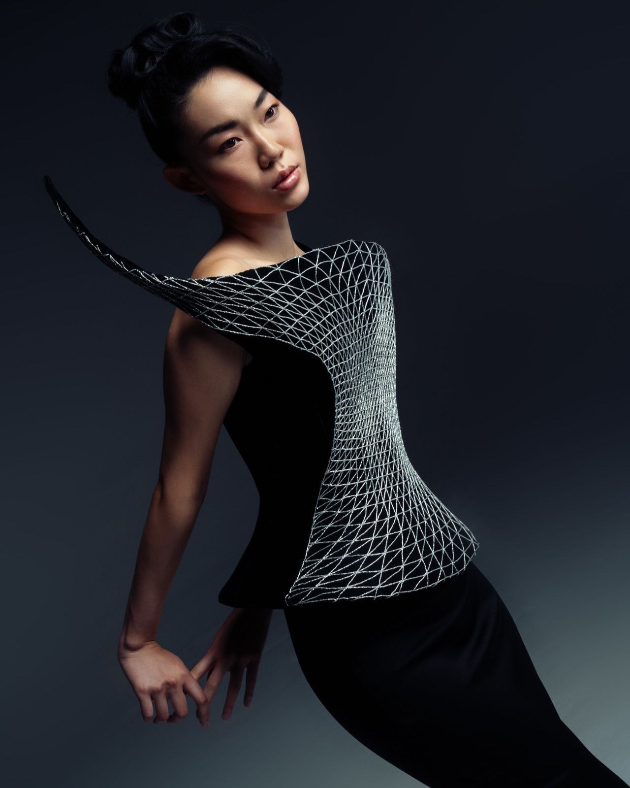 Woman wearing a black dress with a geometric white pattern on a dark background