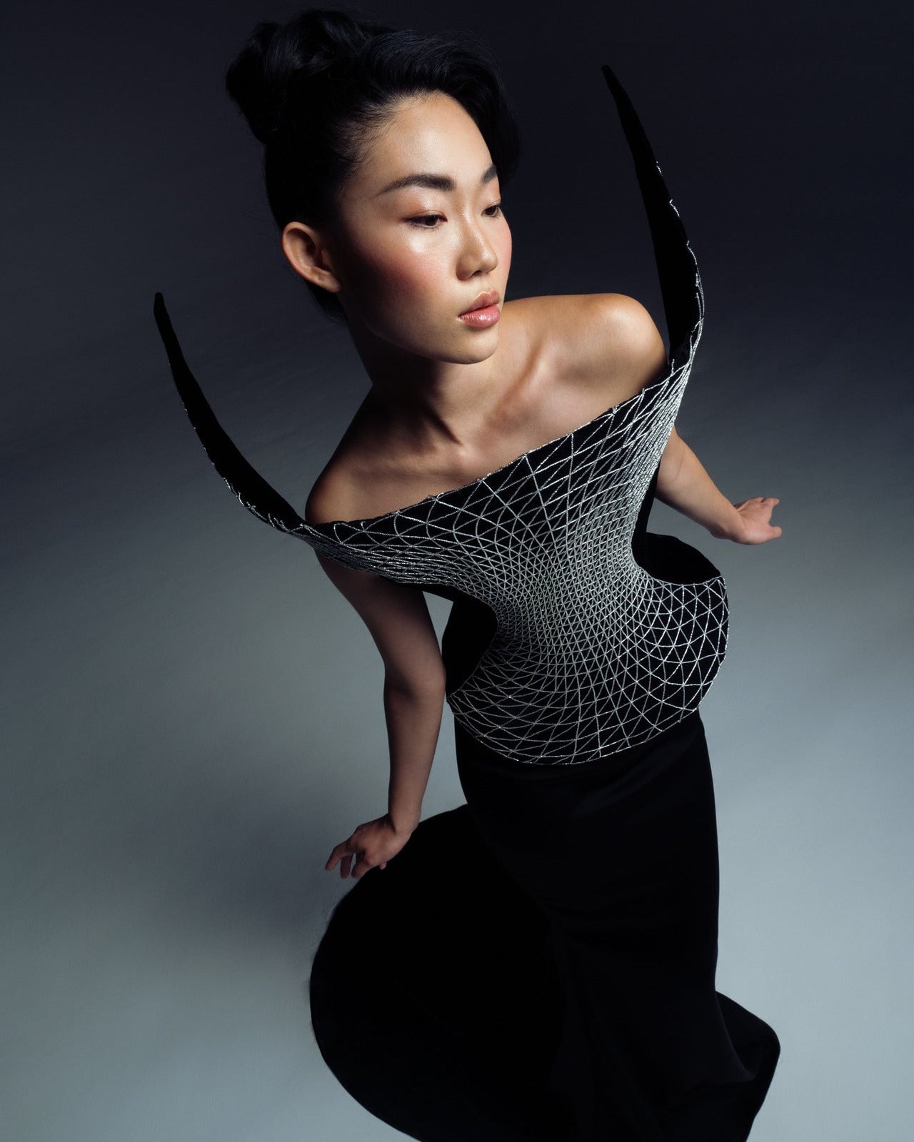 Model wearing a black, textured top with a gray background