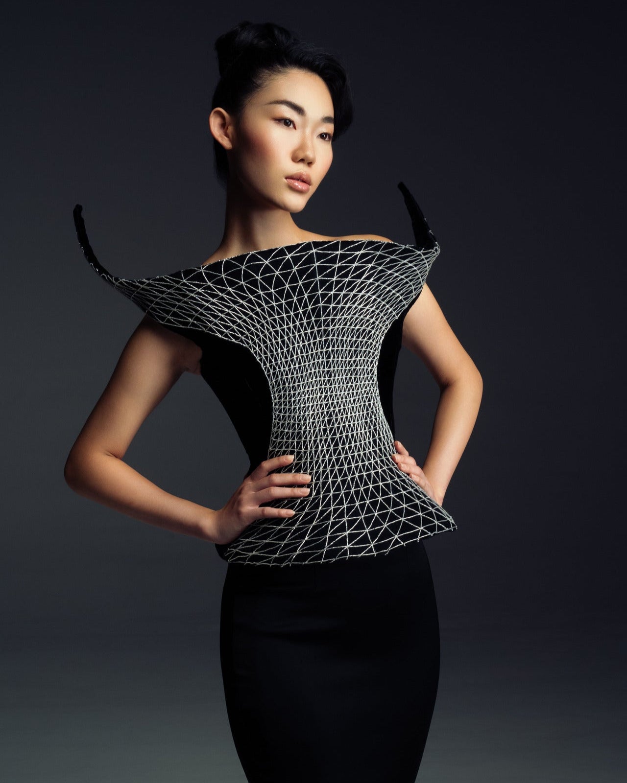 Woman wearing a futuristic black and silver top against a dark background